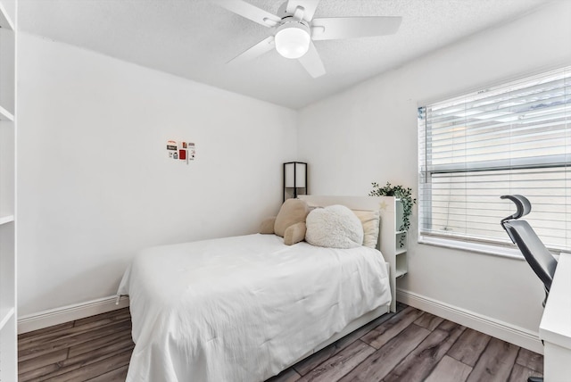 bedroom with ceiling fan, dark wood-type flooring, and a textured ceiling