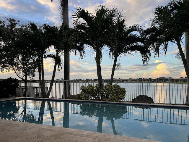 pool at dusk featuring a water view