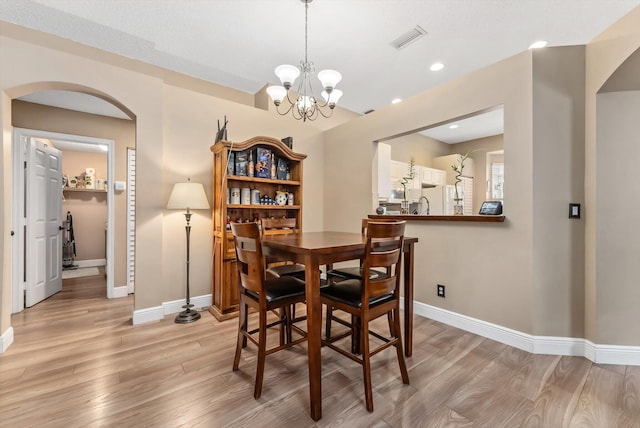 dining room featuring light wood-type flooring and a notable chandelier