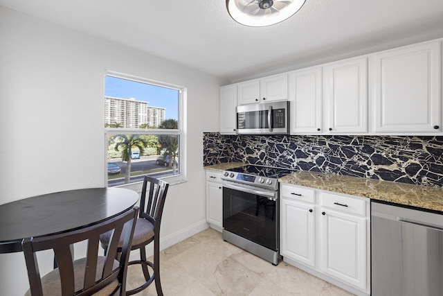 kitchen with white cabinets, stainless steel appliances, and dark stone counters