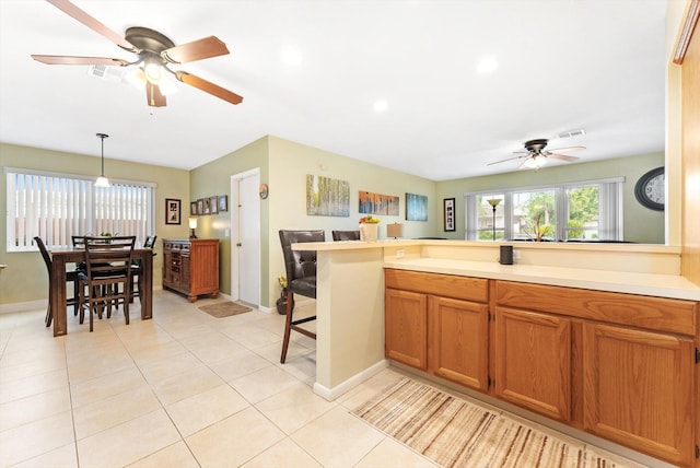 kitchen with a breakfast bar, light tile patterned floors, hanging light fixtures, and kitchen peninsula