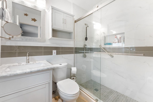 bathroom with toilet, vanity, tile walls, decorative backsplash, and an enclosed shower