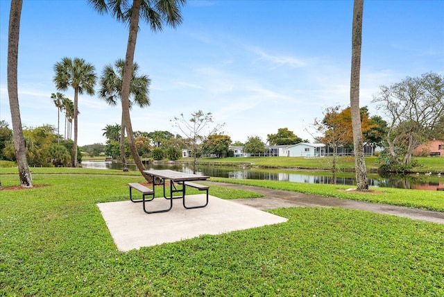 view of property's community with a yard, a water view, and a patio