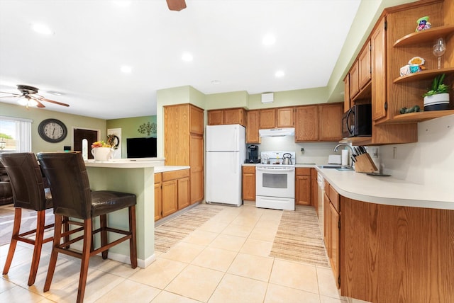 kitchen featuring sink, white appliances, a kitchen breakfast bar, ceiling fan, and light tile patterned floors