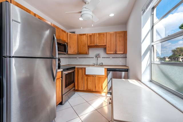 kitchen with sink, light tile patterned floors, ceiling fan, stainless steel appliances, and backsplash