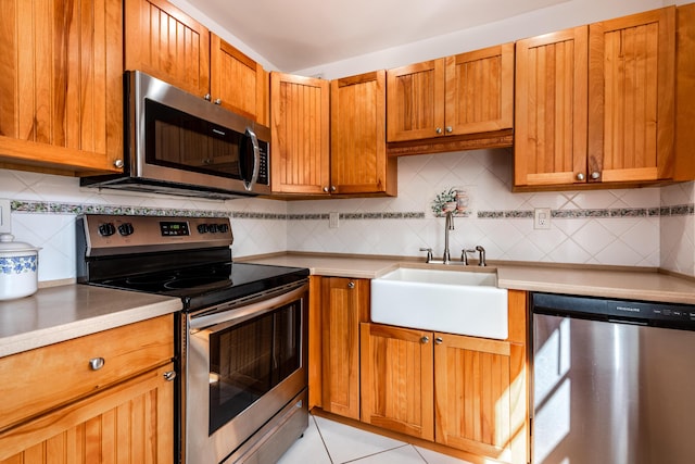 kitchen with light tile patterned flooring, appliances with stainless steel finishes, sink, and backsplash