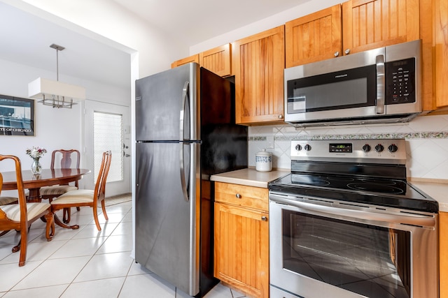 kitchen featuring tasteful backsplash, stainless steel appliances, light tile patterned flooring, and hanging light fixtures