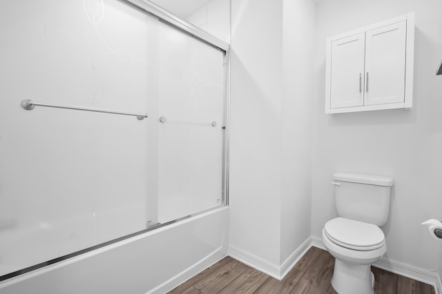 bathroom featuring wood-type flooring, toilet, and combined bath / shower with glass door