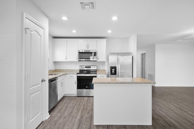 kitchen featuring appliances with stainless steel finishes, white cabinetry, sink, a center island, and light hardwood / wood-style flooring