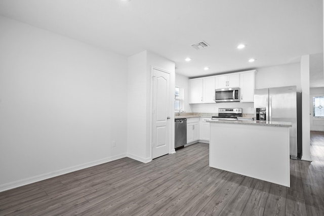 kitchen featuring a center island, light hardwood / wood-style flooring, a wealth of natural light, stainless steel appliances, and white cabinets