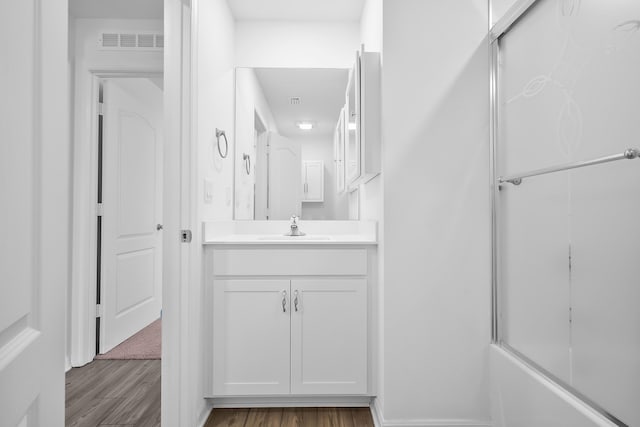 bathroom featuring vanity, wood-type flooring, and enclosed tub / shower combo