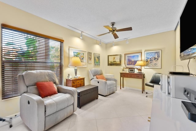 living area featuring a textured ceiling, rail lighting, ceiling fan, and light tile patterned floors