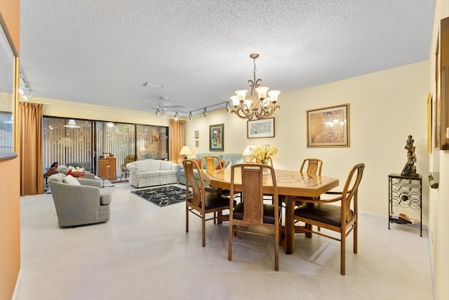 dining area featuring ceiling fan with notable chandelier, a textured ceiling, rail lighting, and light tile patterned floors