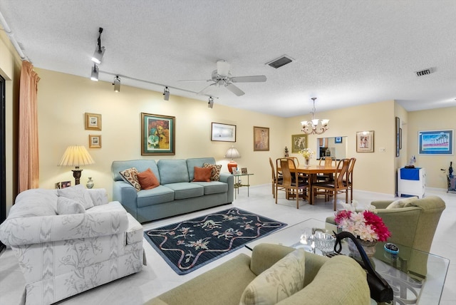 tiled living room featuring ceiling fan with notable chandelier, track lighting, and a textured ceiling