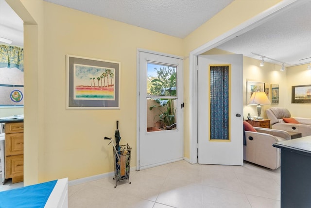 tiled foyer with rail lighting and a textured ceiling