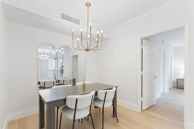 dining room featuring crown molding, light wood-type flooring, and a notable chandelier