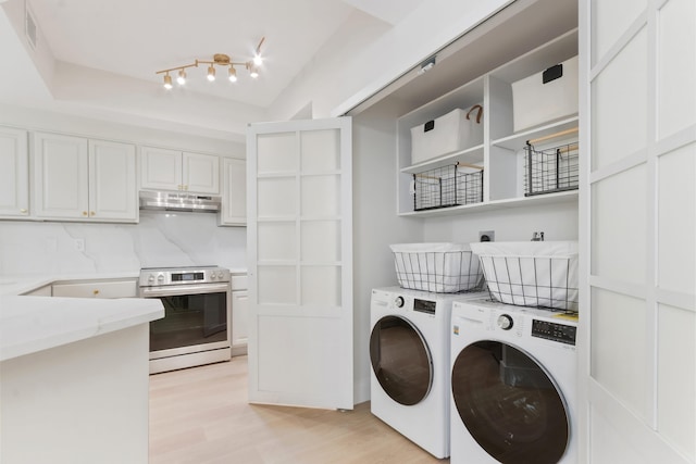 clothes washing area featuring washing machine and dryer and light hardwood / wood-style flooring