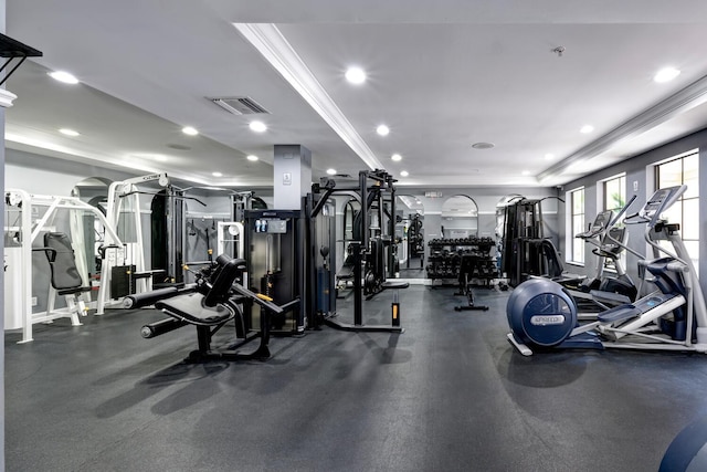 workout area featuring ornamental molding and a raised ceiling