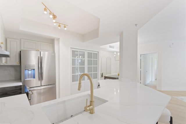 kitchen featuring stainless steel appliances, light stone countertops, sink, and light wood-type flooring