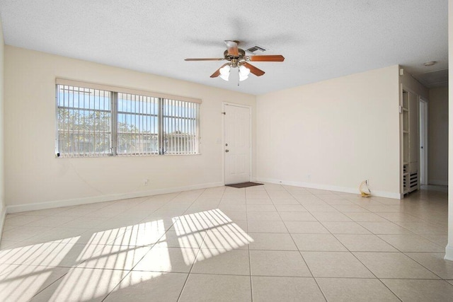 unfurnished room featuring a textured ceiling, ceiling fan, and light tile patterned flooring