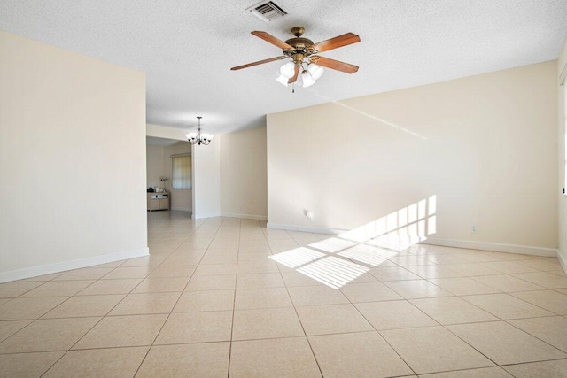 tiled spare room featuring ceiling fan with notable chandelier