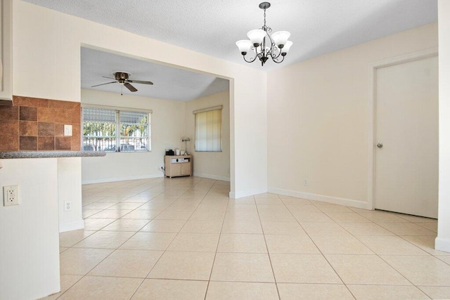 tiled empty room with a textured ceiling and ceiling fan with notable chandelier