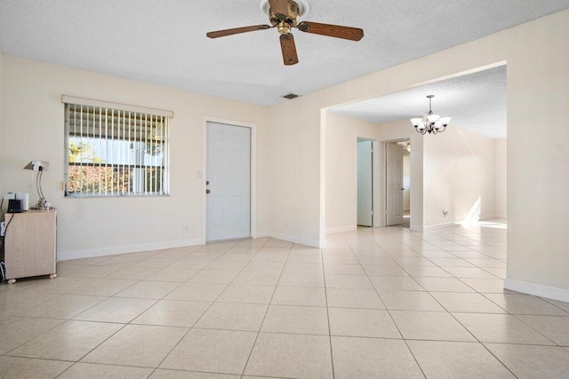 tiled spare room featuring a textured ceiling and ceiling fan with notable chandelier