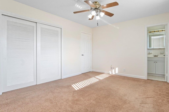 unfurnished bedroom featuring ceiling fan, a closet, light carpet, and ensuite bath