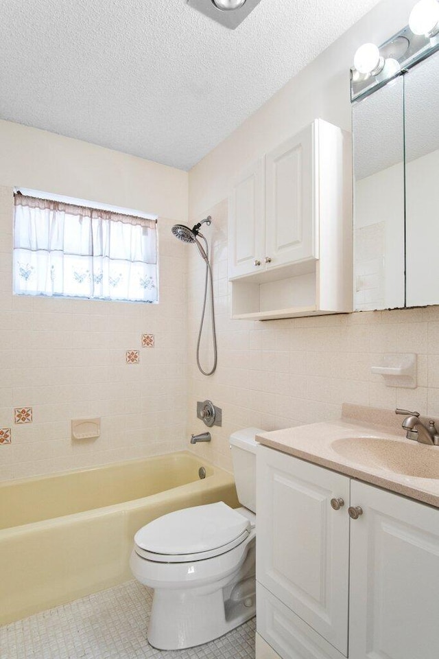 full bathroom with tile patterned flooring, vanity, tiled shower / bath combo, and toilet