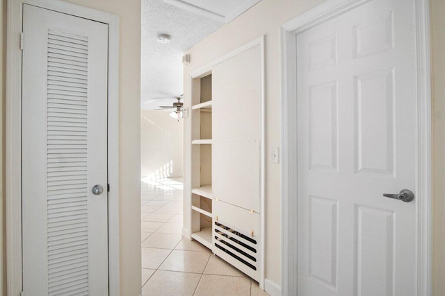 hall with a textured ceiling and light tile patterned flooring