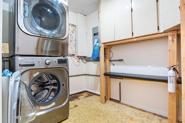 laundry area with cabinets, stacked washer and dryer, and electric panel