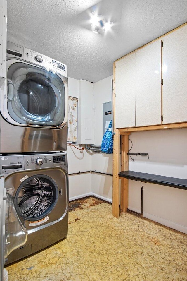 washroom featuring a textured ceiling and stacked washer and clothes dryer