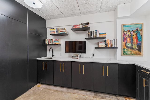 bar with sink, light stone countertops, and built in desk