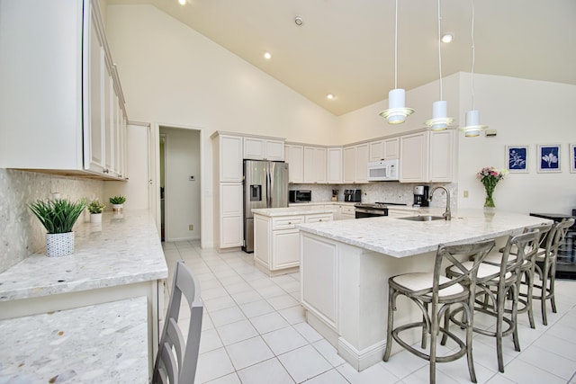 kitchen with pendant lighting, appliances with stainless steel finishes, sink, high vaulted ceiling, and a center island with sink