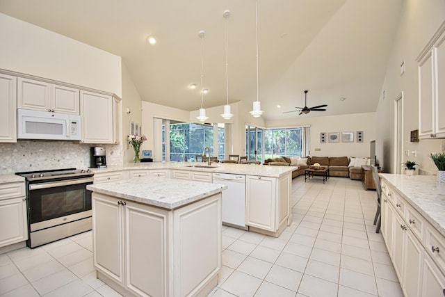 kitchen with white appliances, decorative backsplash, sink, a kitchen island, and pendant lighting