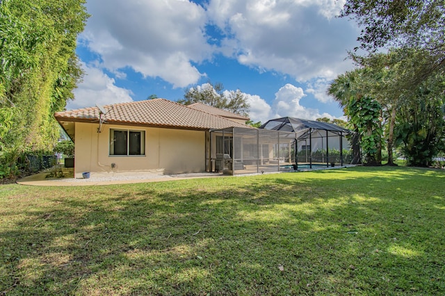 back of house featuring glass enclosure and a yard