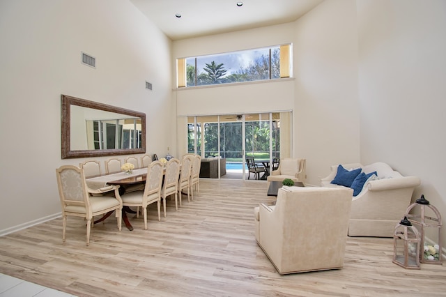 living room featuring light hardwood / wood-style flooring and a towering ceiling