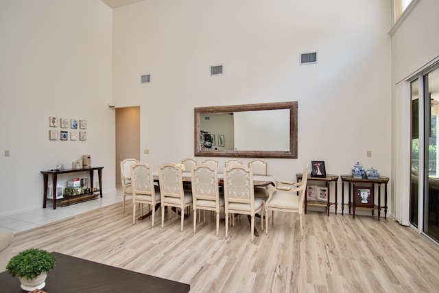 dining space with a high ceiling and light wood-type flooring