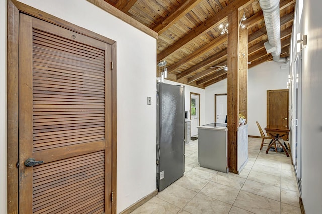 kitchen with wooden ceiling, black refrigerator, light tile patterned floors, and vaulted ceiling with beams