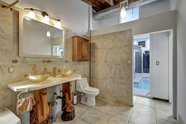 bathroom featuring toilet, tile walls, and vanity