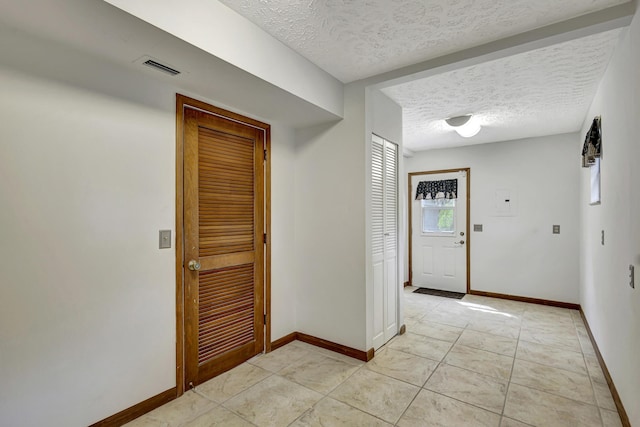 corridor with a textured ceiling and light tile patterned floors