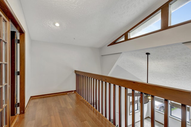 hall featuring a textured ceiling, lofted ceiling, and wood-type flooring