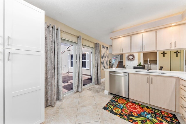 kitchen featuring sink, stainless steel dishwasher, light tile patterned floors, a textured ceiling, and kitchen peninsula