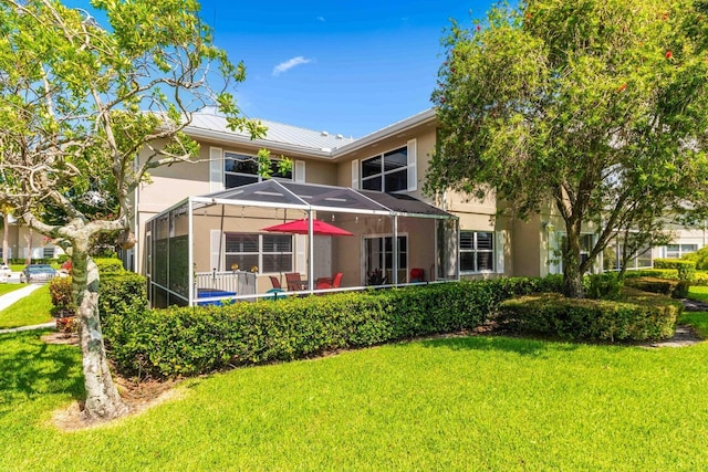 rear view of property featuring a lawn and glass enclosure