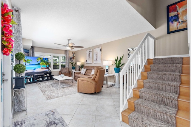 living room with ceiling fan, light tile patterned floors, and a textured ceiling