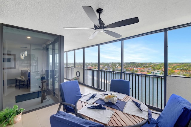 sunroom featuring ceiling fan and a water view