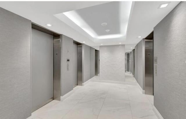 corridor featuring a tray ceiling and elevator