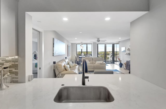 kitchen with light stone countertops, a wall of windows, tasteful backsplash, and sink