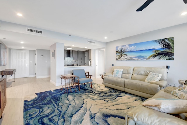 living room with light wood-type flooring, ceiling fan, and sink