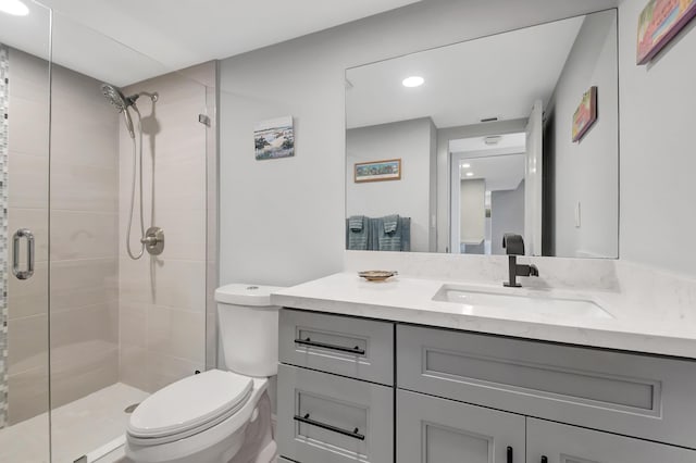 bathroom with toilet, a shower with shower door, and vanity